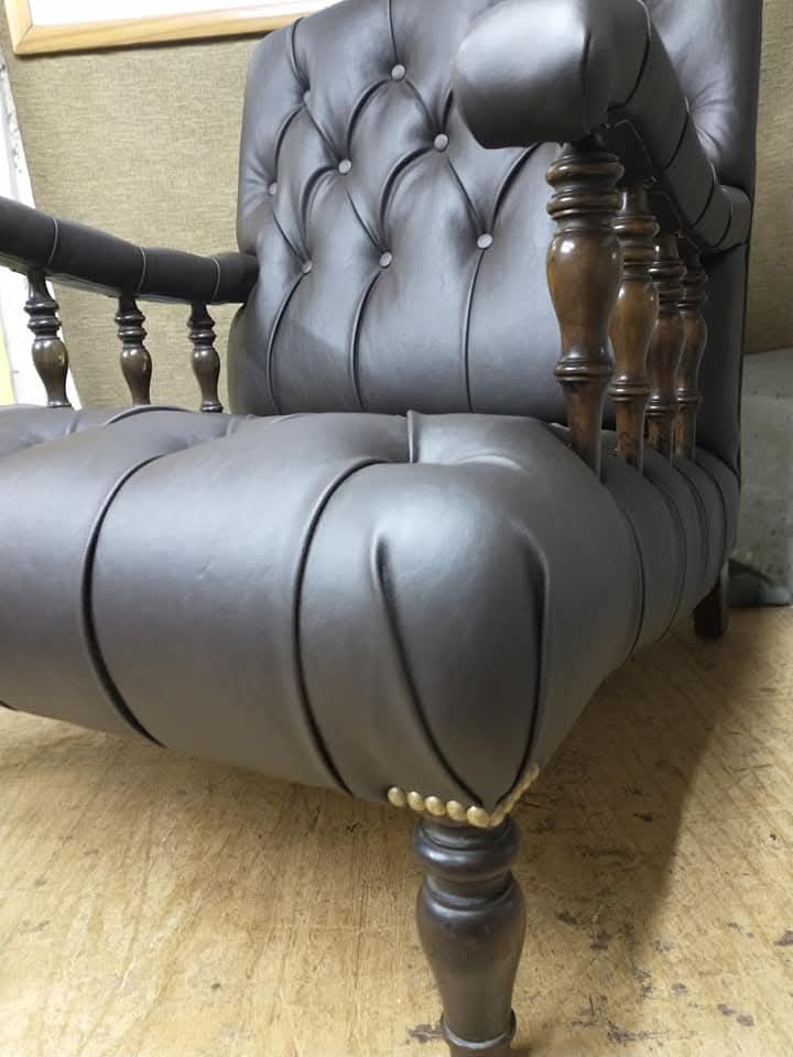 Sillón capitoné de cuerina oscura con tachas, trabajo de Tapicería MH